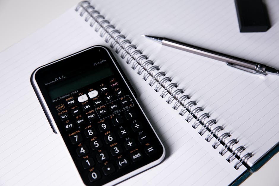 Close-up of a calculator, spiral notebook, and pen on a desk, ideal for office or educational themes.